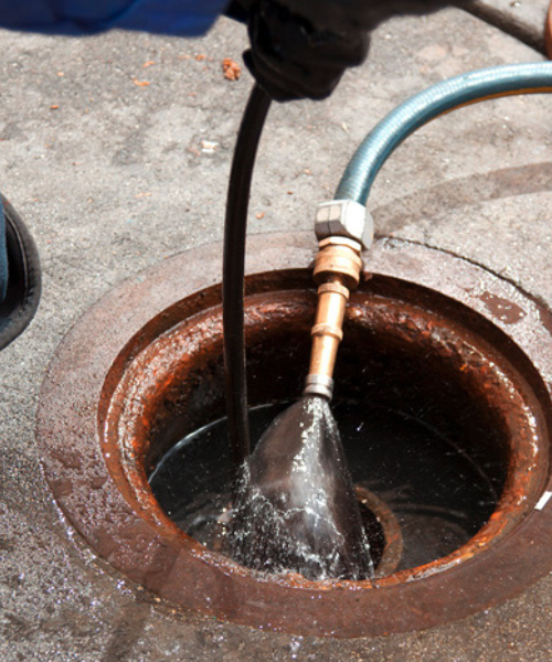 A man is pouring water into a manhole