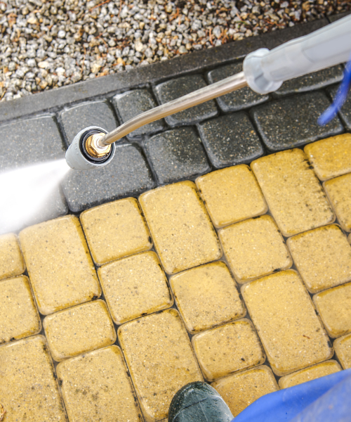 A person is spraying water on a sidewalk