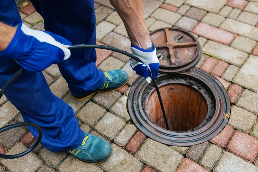 A man is using a hose to clean a manhole